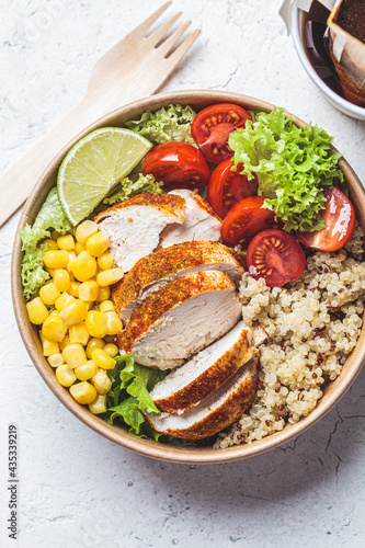 Close-up of chicken and quinoa salad with corn and tomatoes in craft eco bowl. Zero waste, to go food, recycling packaging, eco friendly concept.