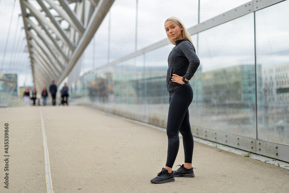 Fit Woman in Black Workout Outfit Standing At Modern Bridge In City Fit Woman in Black Workout Outfit Standing At Modern Bridge In City