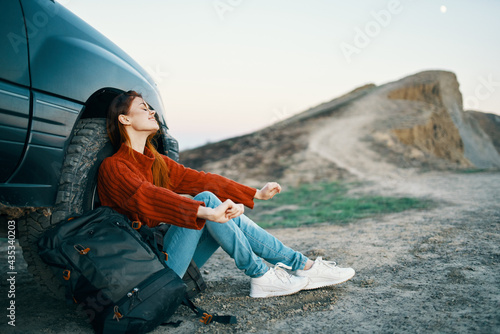 woman travels on nature in the mountains near the car with a backpack on the side