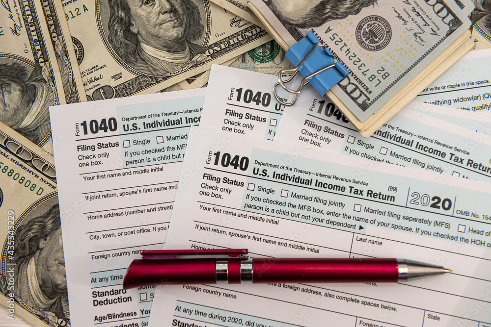 1040 tax form with pen and US dollar bills 1040 tax form with pen and US dollar bills