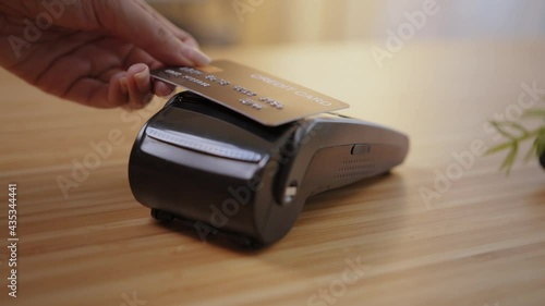 Close-up woman customer hand using credit card tap to pay on purchase machine to pay bill. Contactless and cashless technology  tap-and-go payment concept.