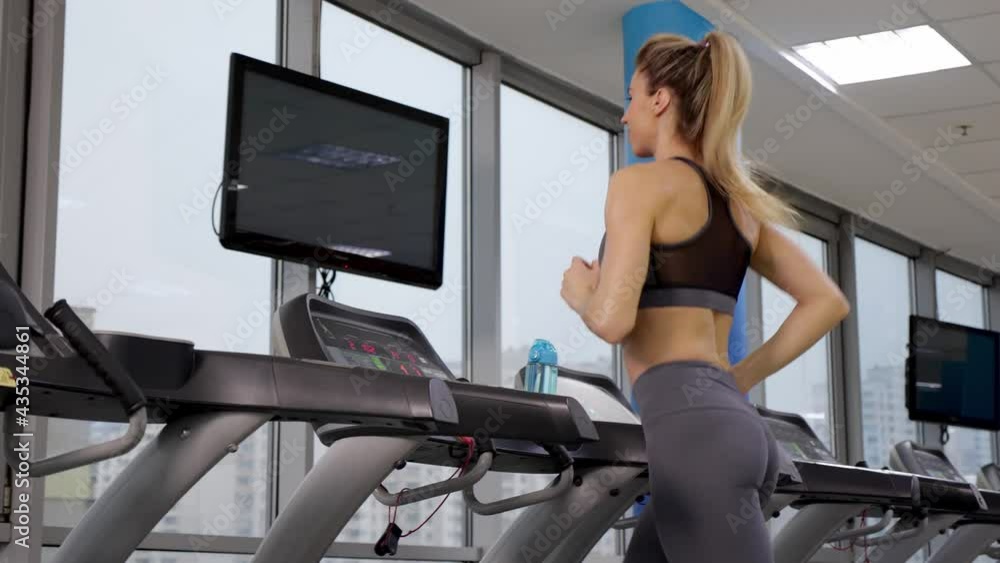 Young sporty Woman On Running Machine In Gym Young sporty Woman On Running Machine In Gym