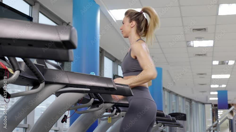 Young sporty Woman On Running Machine In Gym Young sporty Woman On Running Machine In Gym