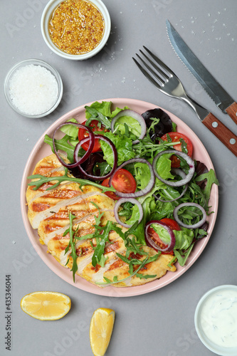 Concept of tasty eating with salad with grilled chicken on gray background