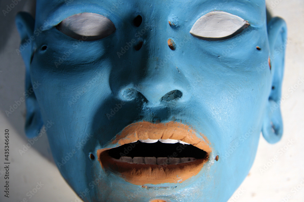 Fototapeta premium Blue female face with shadows. White eyes, smooth skin: expressive sculpture in the process of creation.