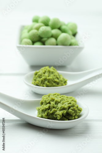 Tasty wasabi nuts and sauce on white wooden background