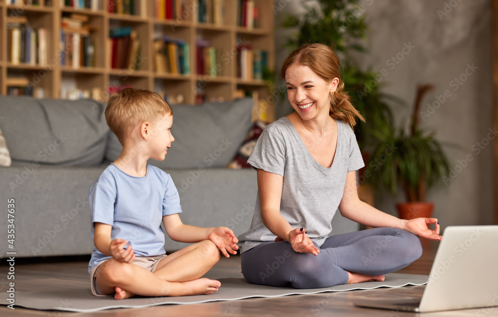 Healthy family mom and son meditating together at home while having online yoga class on laptop Healthy family mom and son meditating together at home while having online yoga class on laptop