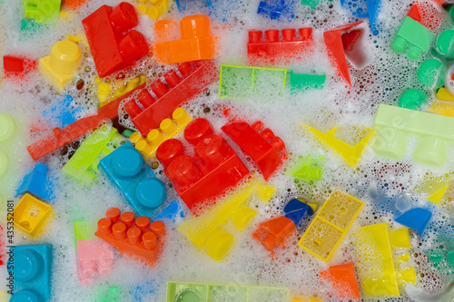 cleaning colorful toy building blocks. toys hygiene. washing plastic toys in bath with foam