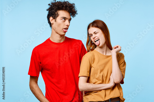 cheerful young couple in multicolored t-shirts communication studio blue background