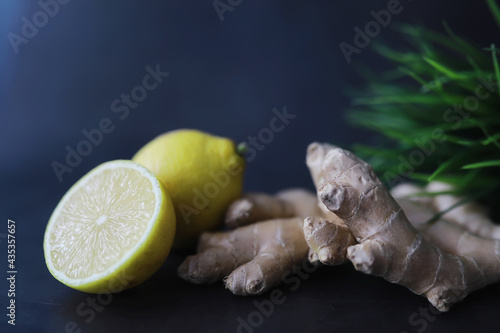 Fototapeta Naklejka Na Ścianę i Meble -  Ginger root whole and sliced. Ginger tea with lemon on the dark background. Fresh ginger root on stone background. Vitamins. Free space for your text.