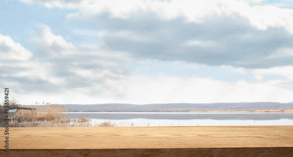 empty space on a wooden table for your product on the background of an abstract lake, a river with mountains