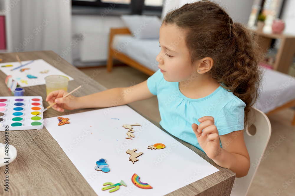 childhood, hobby and leisure concept - little girl with brush painting wooden chipboard items at home childhood, hobby and leisure concept - little girl with brush painting wooden chipboard items at home