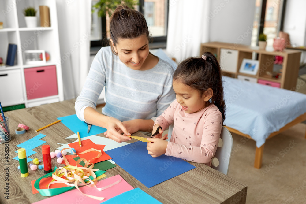 family, art and craft concept - mother spending time with her little daughter with glue making applique of color paper at home family, art and craft concept - mother spending time with her little daughter with glue making applique of color paper at home