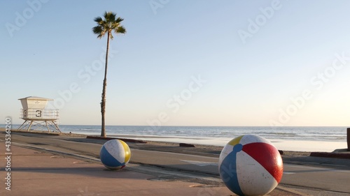 Pacific ocean beach, Oceanside California USA. Ball, lifeguard tower, life guard watchtower hut and tropical palm tree, sky, beachfront street, waterfront road. Los Angeles vibes, aesthetic atmosphere
