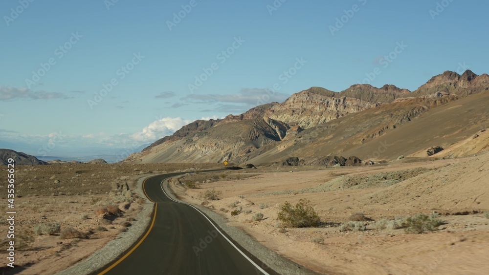 Road trip to Death Valley, Artists Palette drive, California USA. Hitchhiking auto traveling in America. Highway, colorful bare mountains and arid climate wilderness. View from car. Journey to Nevada.