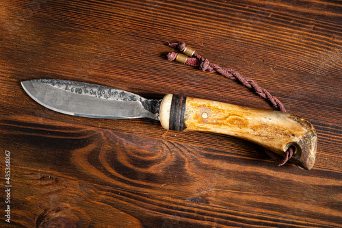 Hunting knife handmade on a wooden background