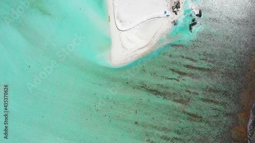 Aerial Panning The Sandy Shoreline Of A Small Tropical Island Surrounded By Turquoise Colored Water And Drenched In Bright Sunlight - Dhiffushee Falhu, Maldives photo