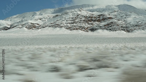 Road trip to Death Valley, driving auto, snow in California, USA. Hitchhiking winter traveling in America. Highway, mountain pass and dry barren wilderness. Passenger POV from car. Journey to Nevada. © Dogora Sun