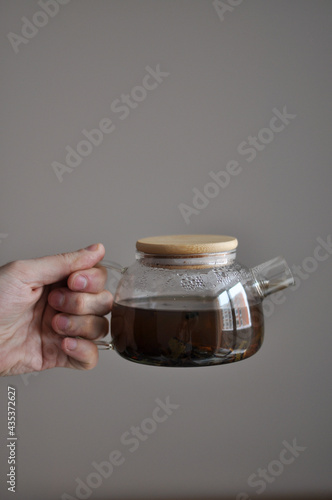 Tea pot male hand morning concept - transparent teapot in a man's hand on white backgrouhd morning routine man's care healthy lifestyle photo