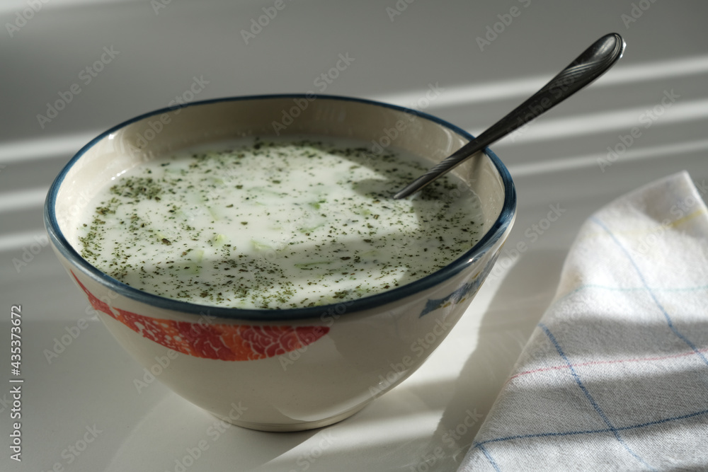 Peppermint tzatin and spoon in a bowl on a white background Peppermint tzatin and spoon in a bowl on a white background