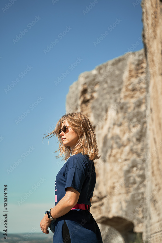 Young woman stay on a rock, looking at the landscape and enjoying the view and fresh air.