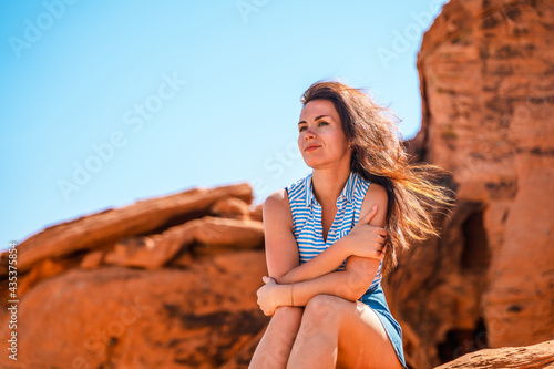 A young woman enjoys a view of the Valley of Fire in Nevada, views of ribbons of red rock slice through the desert landscape.