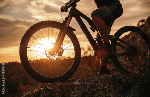 Crop man riding bicycle at sunset photo