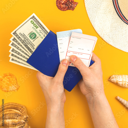 Hand holds airline boarding pass for summer travek and vacation concept background with passport, money and seashells, top view photo photo