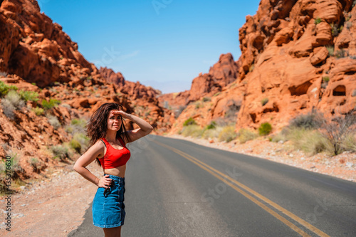 A beautiful young slender woman walks through the desert in the Valley of Fire in Nevada with an amazing landscape in the background.