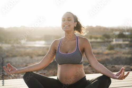 Young pregnant woman doing yoga outdoor - Meditation and maternity concept for an healthy lifestyle - Focus on face © DisobeyArt