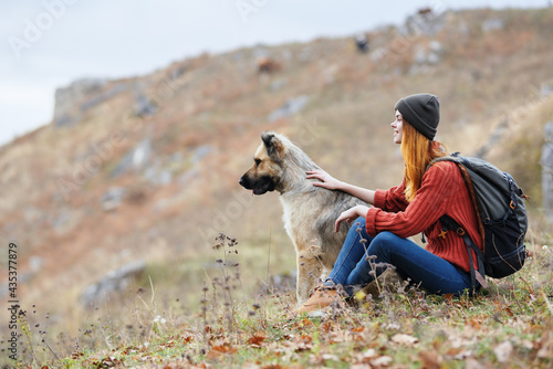 cheerful woman hiker in the mountains outdoors next to the dog travel vacation
