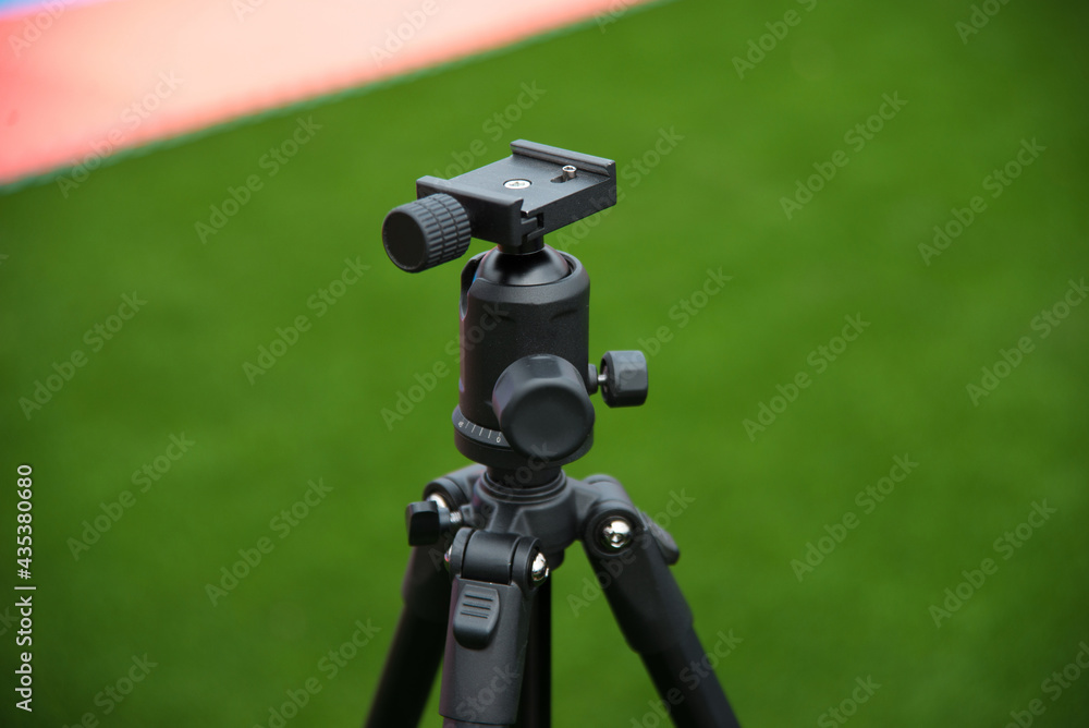 Close up photo of tripod with ball head for camera on stadium Close up photo of tripod with ball head for camera on stadium