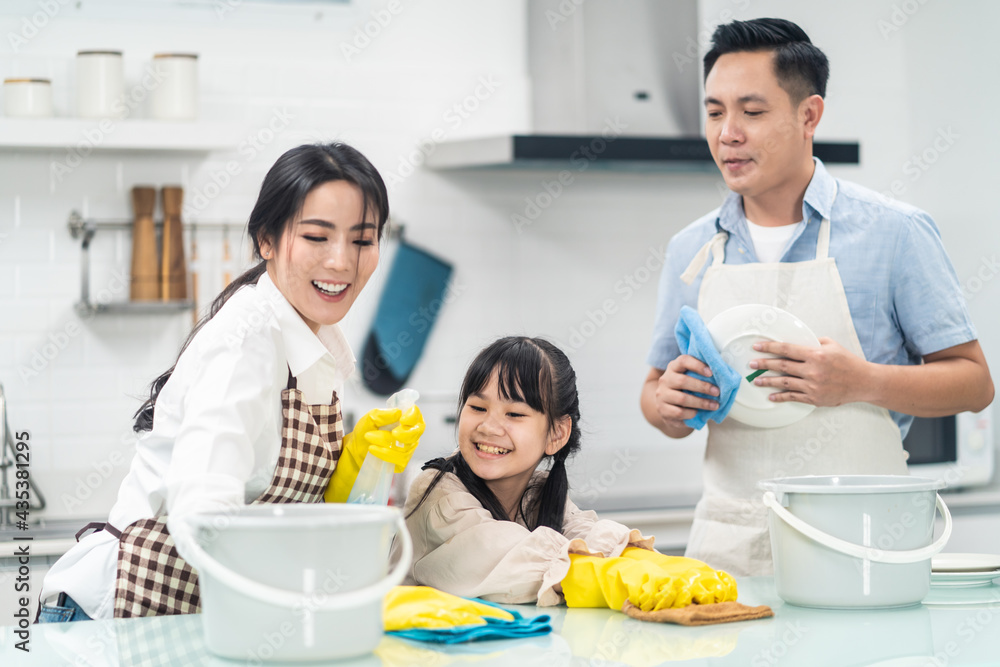 Asian family helping each other to clean kitchen counter and housework	