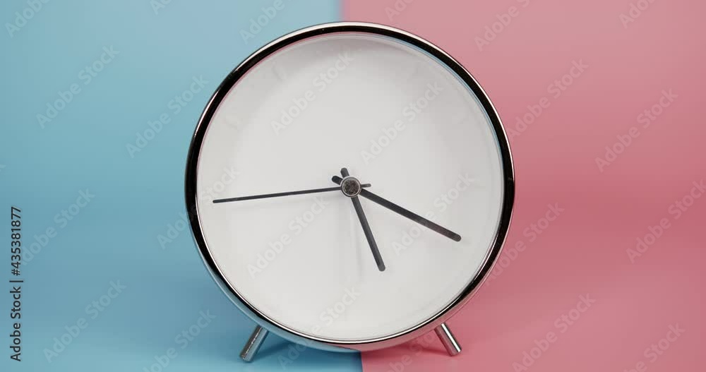 Silver Alarm clock isolated on blue pink background, Time starts walking at 5o'clock, Time lapse 4 hour. Silver Alarm clock isolated on blue pink background, Time starts walking at 5o'clock, Time lapse 4 hour.