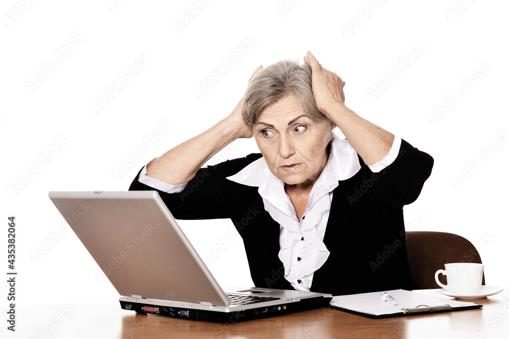 Serious elderly woman doctor sitting at table with computer Serious elderly woman doctor sitting at table with computer