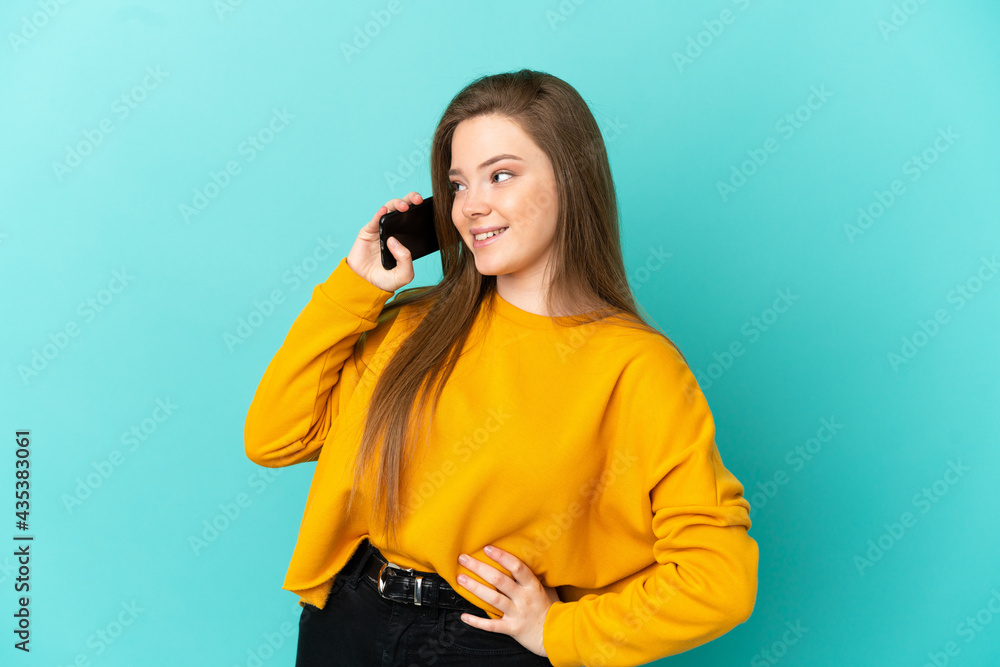 Teenager girl over isolated blue background keeping a conversation with the mobile phone Teenager girl over isolated blue background keeping a conversation with the mobile phone