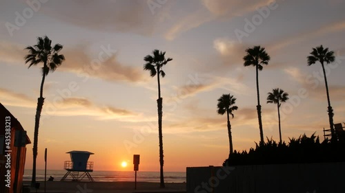 Palms silhouette sunset sky, California aesthetic. Oceanside USA. Tropical pacific ocean beach atmosphere. Dark black palm tree, Los Angeles vibes. Lifeguard watchtower, baywatch watch tower hut.
