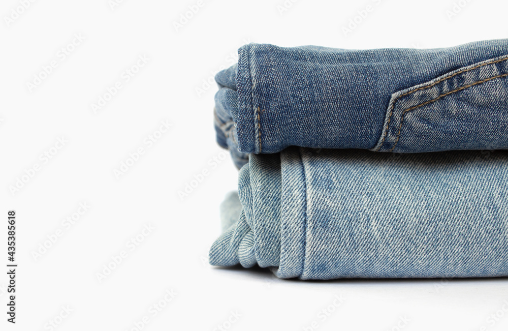 stack of blue jeans isolated on white background, space for text, close-up stack of blue jeans isolated on white background, space for text, close-up