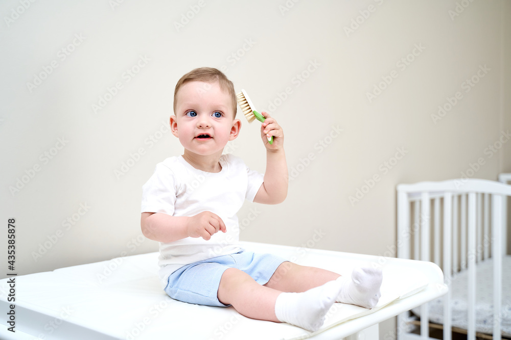 Fototapeta premium a small child with blue eyes holds a comb in his hands