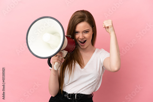 Teenager girl over isolated pink background shouting through a megaphone to announce something