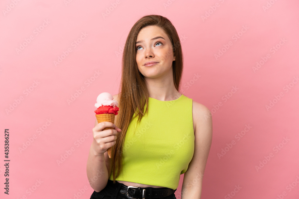 Teenager girl with a cornet ice cream over isolated pink background and looking up Teenager girl with a cornet ice cream over isolated pink background and looking up