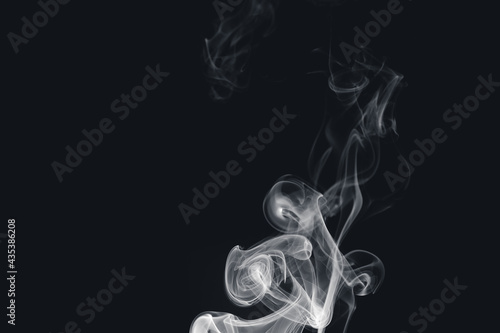 White smoke creating abstract shapes on a black background

