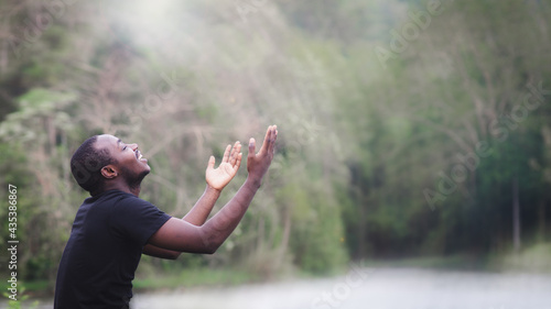Foto African man praying for thank god in the green nature background