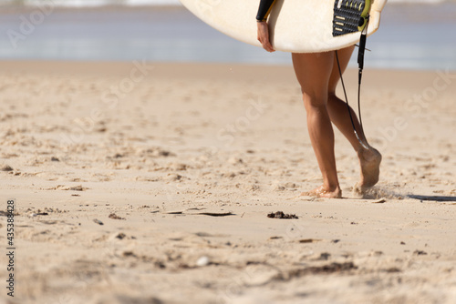 Australian Woman surfer walking along the Beach whit her Surfboard. Noosa, Queensland, Australia