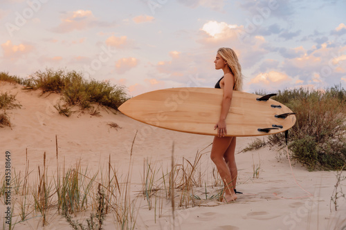 Surfer girl with surfboard on beach and warm sunset colors. Attractive surf women on beach