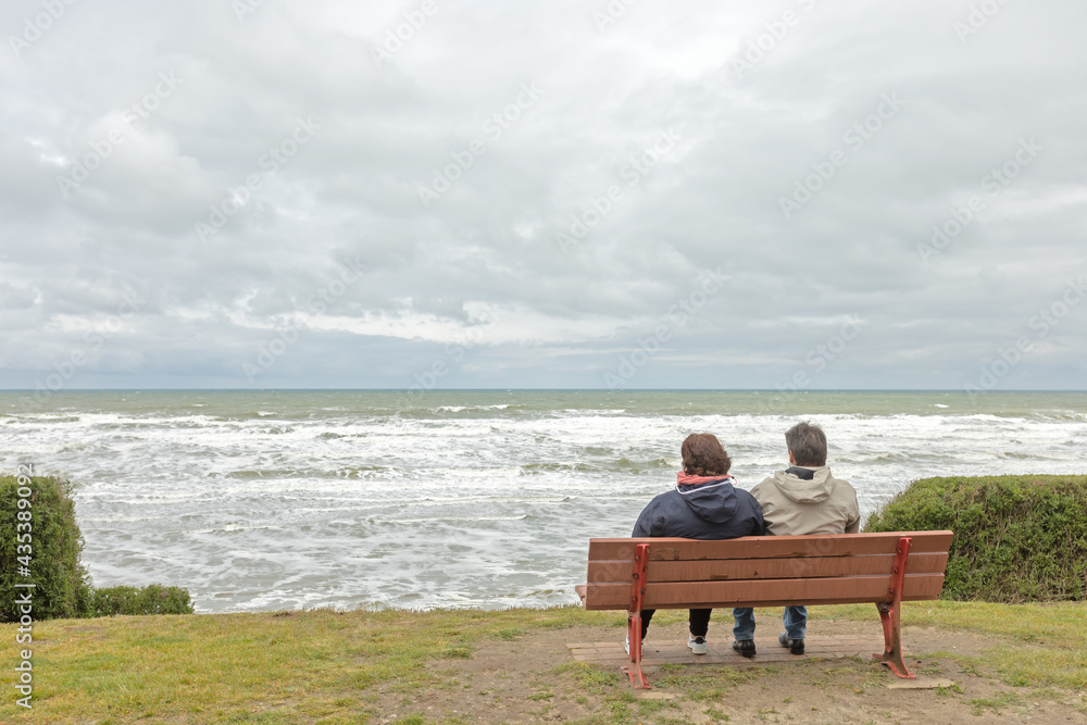 couple assis, sur un banc, regardant la mer