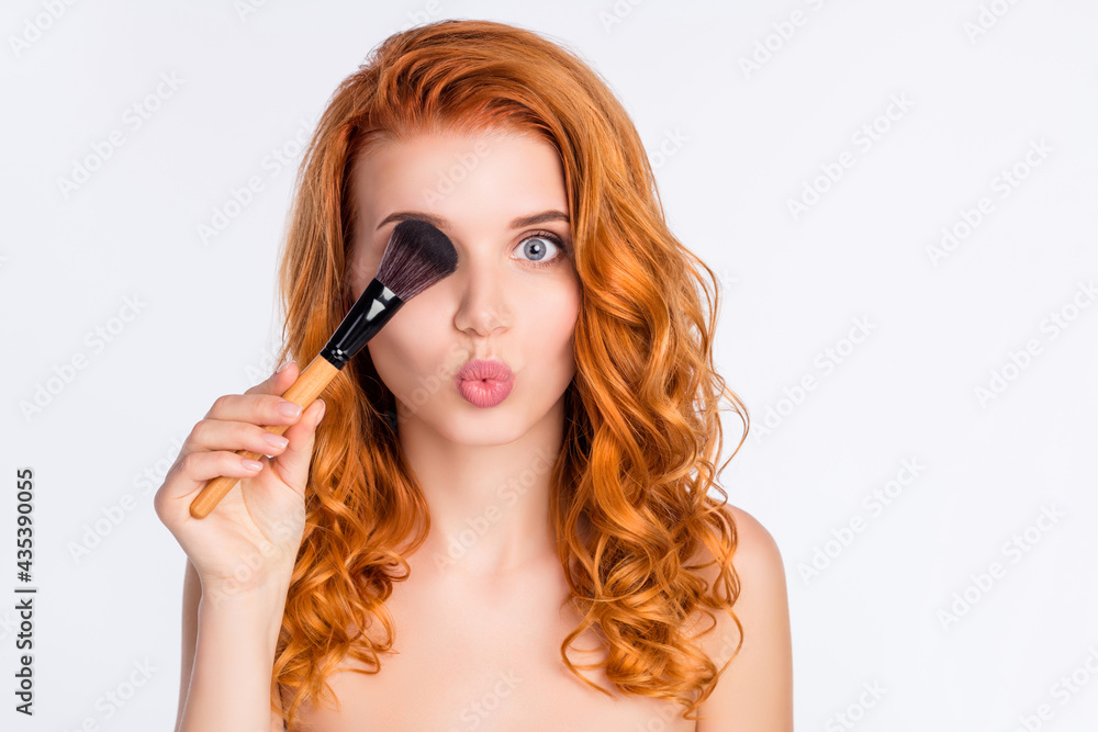 Obraz premium Photo portrait of young model with curly red hair pouted lips keeping make-up brush hiding eye isolated on white color background