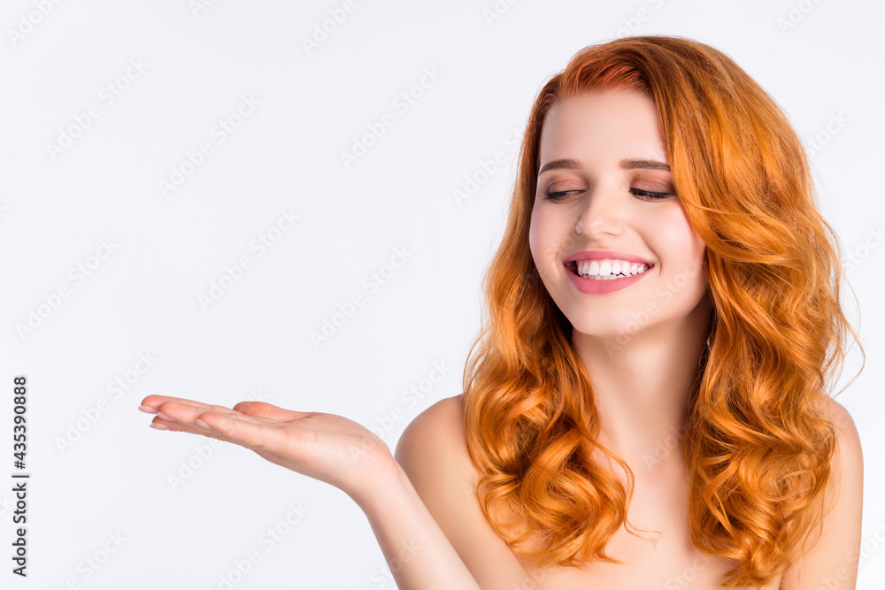 Photo portrait of pretty girl with curly red hair smiling looking keeping blank space on hand isolated on white color background Photo portrait of pretty girl with curly red hair smiling looking keeping blank space on hand isolated on white color background
