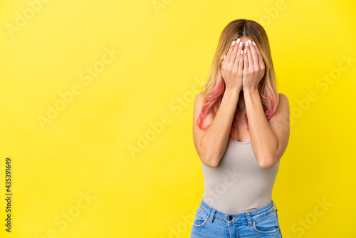 Young woman over isolated yellow background covering eyes by hands