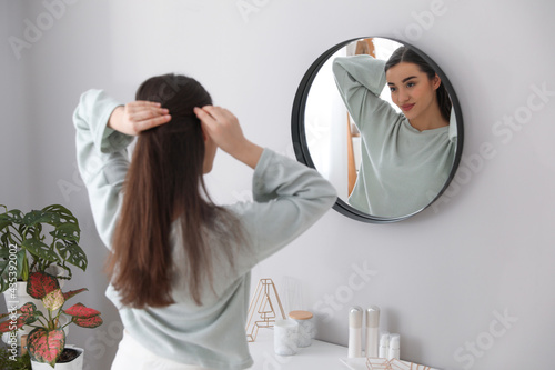 Принти на полотні Young woman doing hair near mirror at home. Morning routine